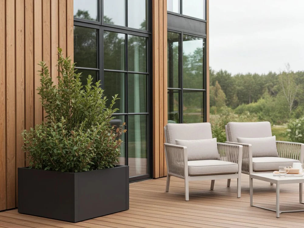 byJEMA CUBY planteringslåda i svartlackerat stål på terrass bredvid loungemöbler