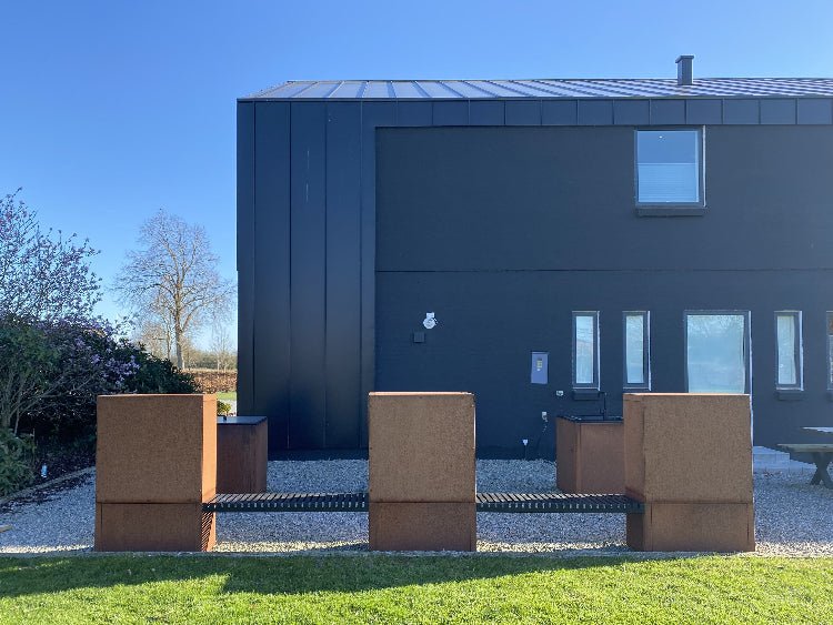 Vedförvaring i cortenstål med sammanhängande sittbänk sedd bakifrån