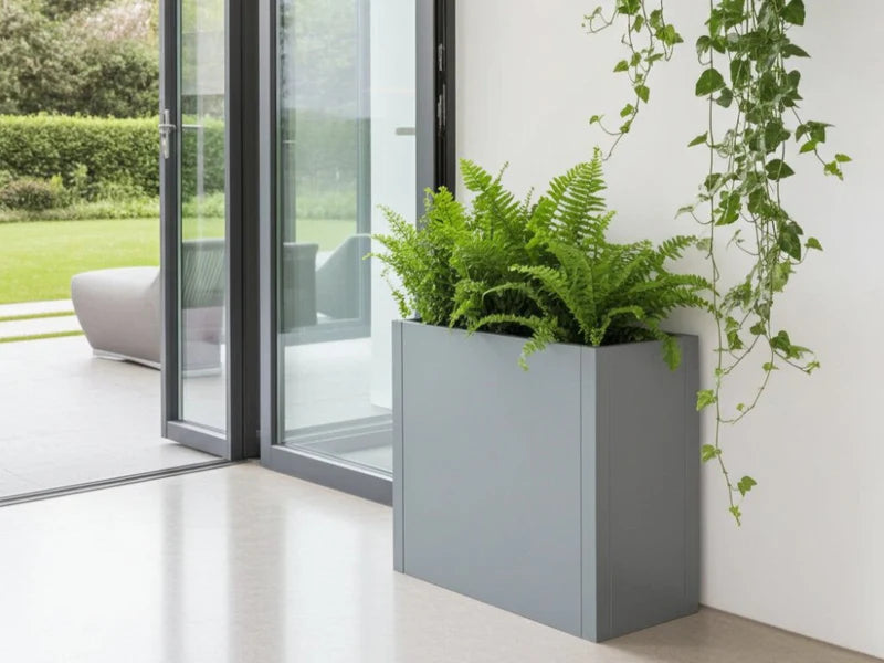 CUBY blomlåda i galvaniserat stål med ormbunkar placerad i ljust hörn