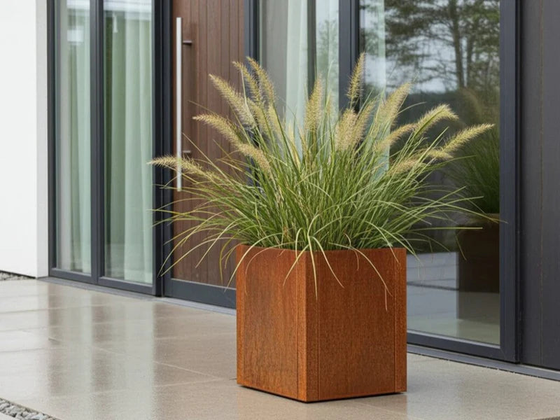 Blomlåda i cortenstål från CUBY med prydnadsgräs vid modern fasad