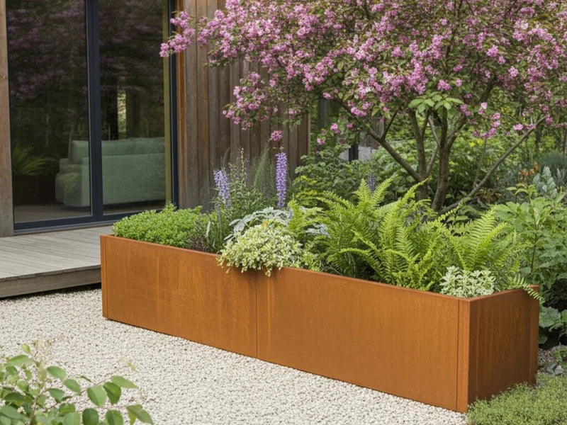 CUBY blomlåda i cortenstål med blommande växter under prydnadsträd