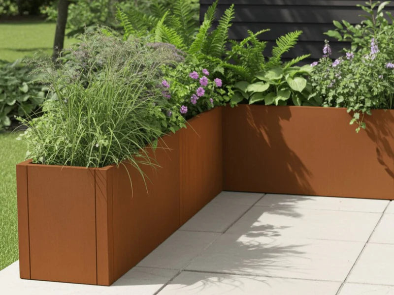 L-formad blomlåda i cortenstål från CUBY med blommande växter i trädgård