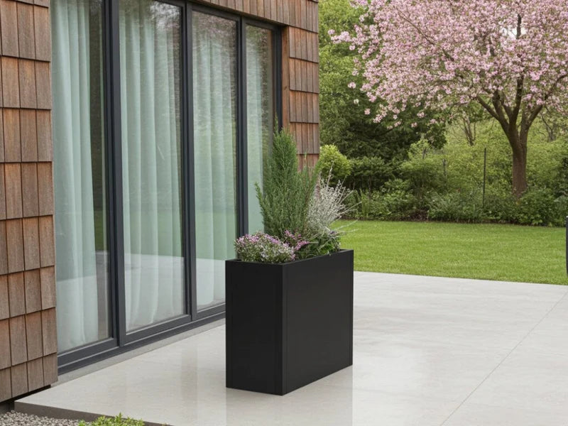 Minimalistisk blomlåda i svart stål vid modernt hus