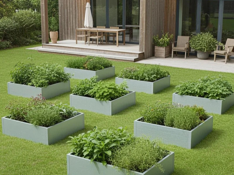 Flera odlingslådor i galvaniserat stål med växter i trädgård vid terrass