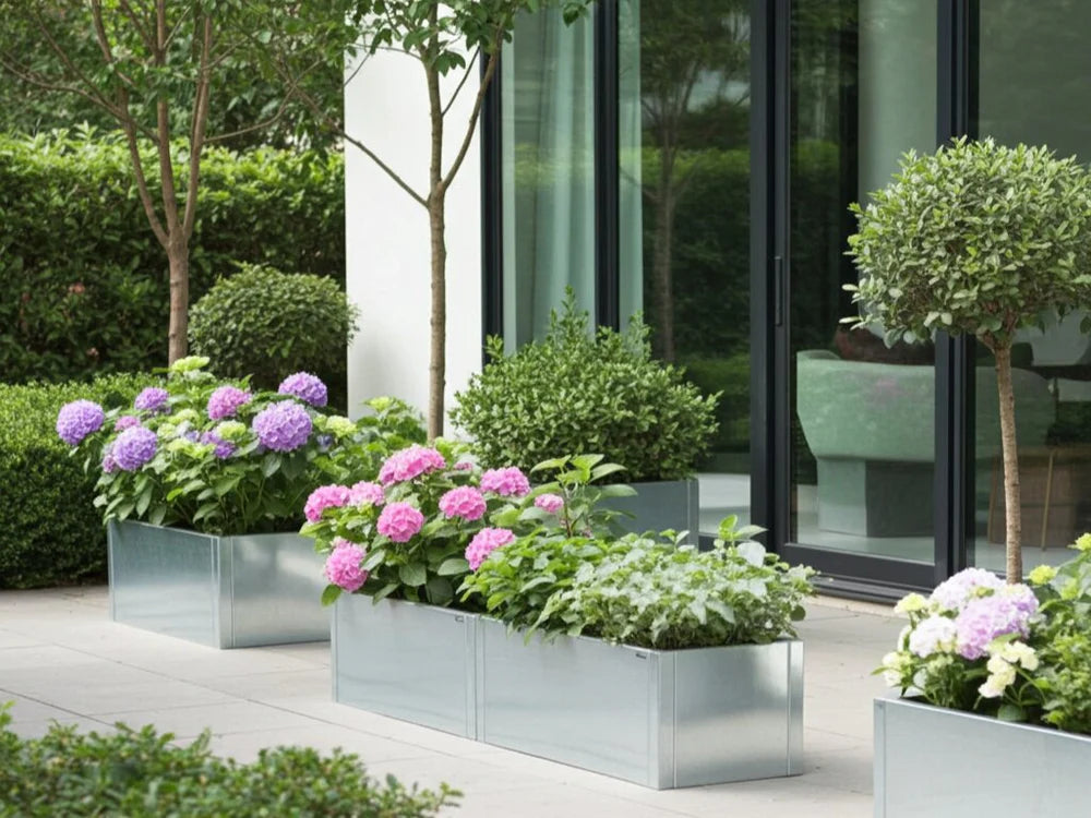 Avlång planteringslåda i galvaniserat stål med blommor och buskar vid uteplats