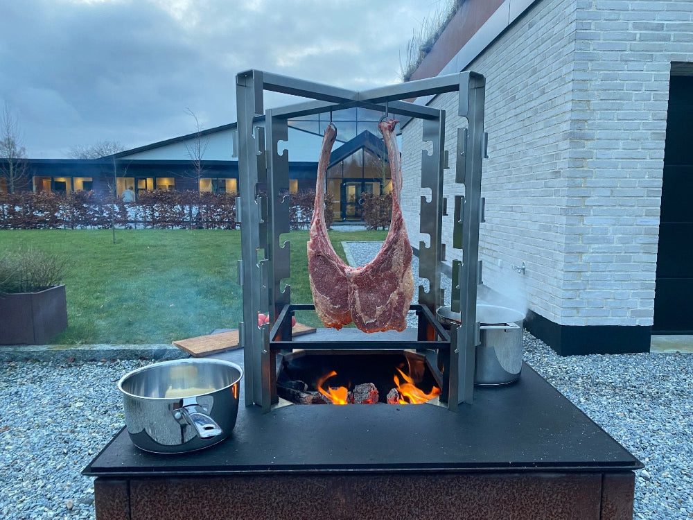 Rotisseri stativ i användning över eld med kött