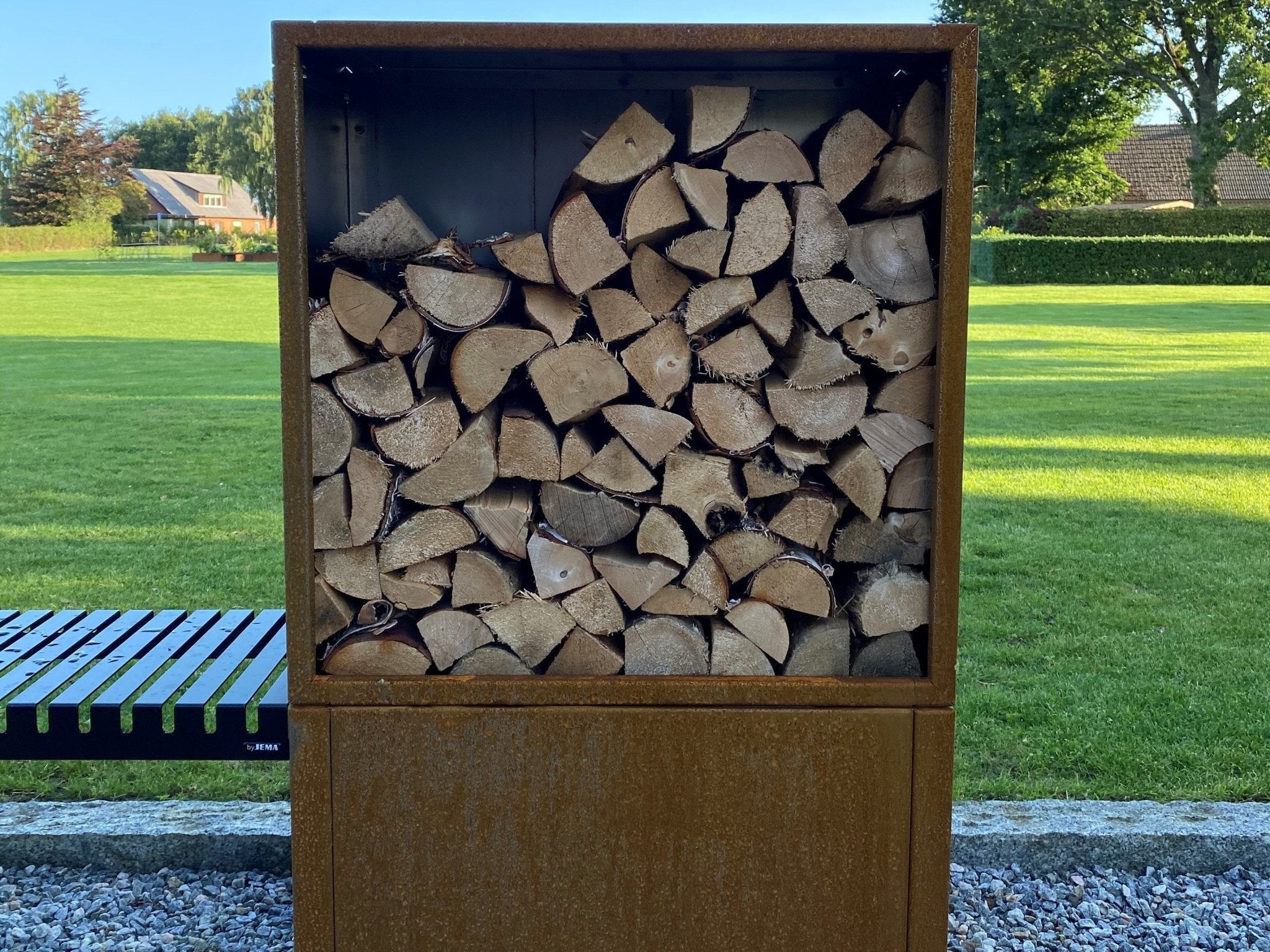 Frontvy av vedförvaring i cortenstål fylld med ved