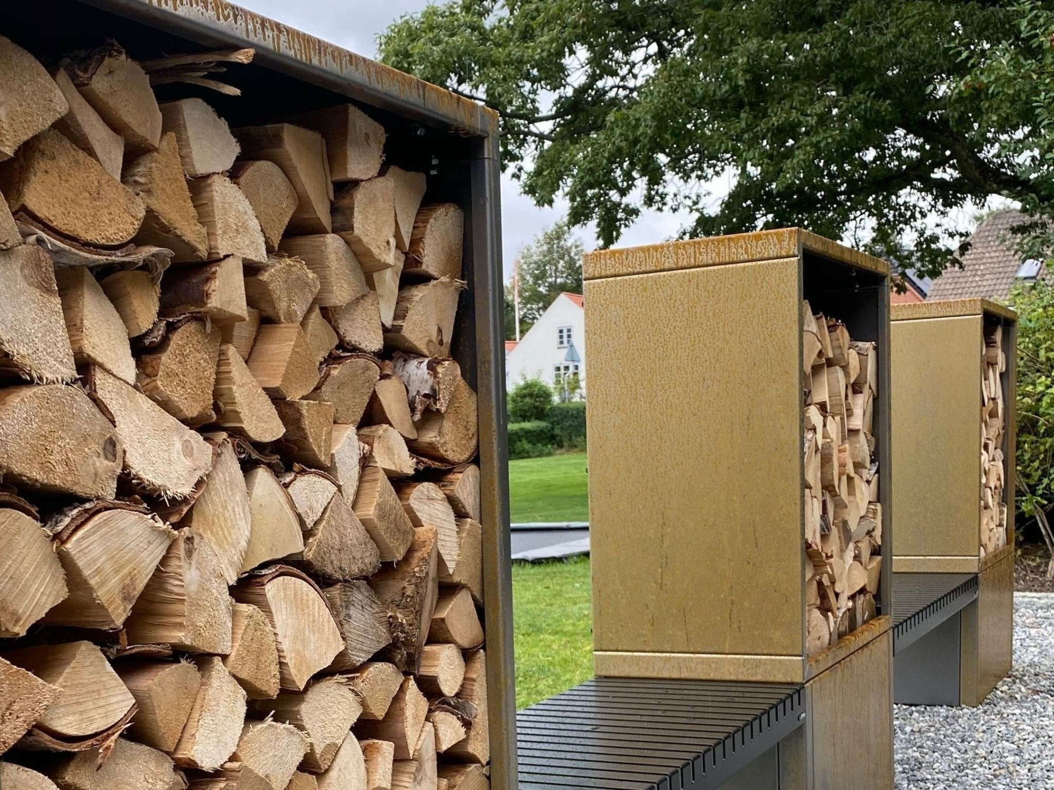Detaljbild av staplad ved i vedställ av cortenstål med sittbänk
