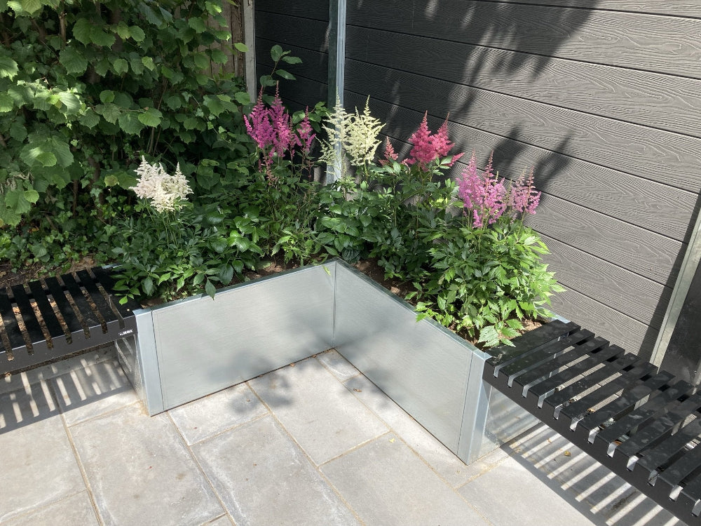 Vinkel blomlåda i galvaniserat stål med blommande växter i trädgård