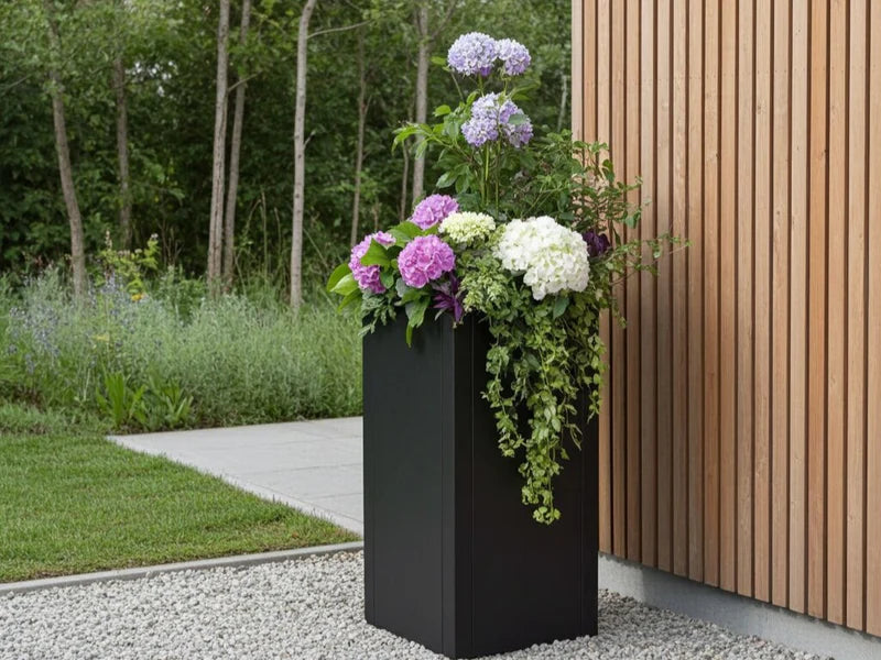 Hög blomkruka i svart stål med blommande hortensia