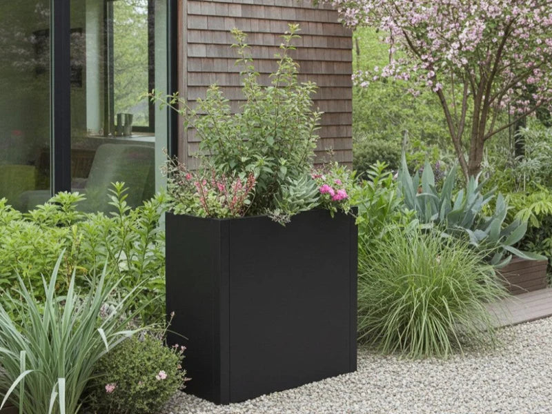 Blomlåda i svart stål med grön plantering i trädgård