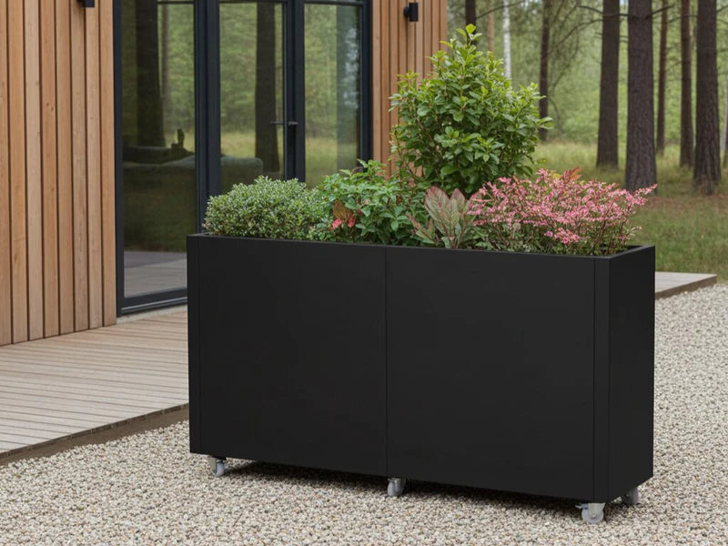 Blomlåda på hjul i svart stål med buskar och blommande växter