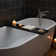 Svartlackerad badkarshylla i stål tvärs över badkar med bok och ljus i spa-inspirerat badrum