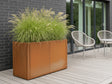 Blomlåda i cortenstål från CUBY fylld med grönska på träterrass