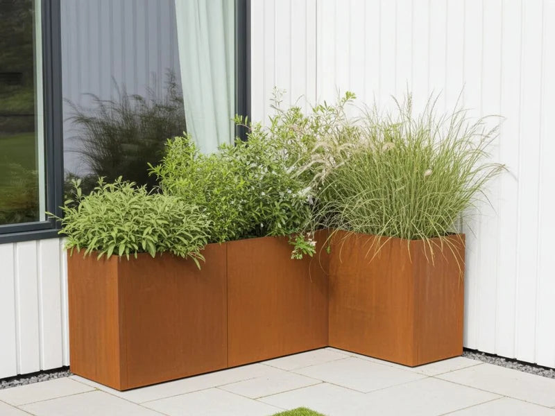 Blomlåda i cortenstål från CUBY som vinkelplantering vid hus