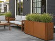 Rektangulär blomlåda i cortenstål från CUBY med prydnadsgräs vid husfasad
