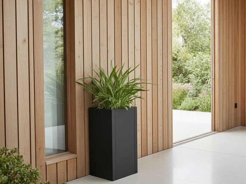 Blomkruka i svart stål vid modern träfasad