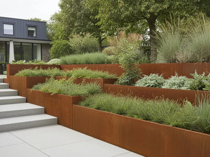 Terrasserad stödmur i cortenstål med perenner vid trappa i trädgård